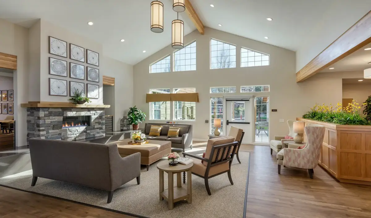 A vaulted great room lit by recessed downlights, lantern pendants and table lamps, with light washing the stone fireplace wall
